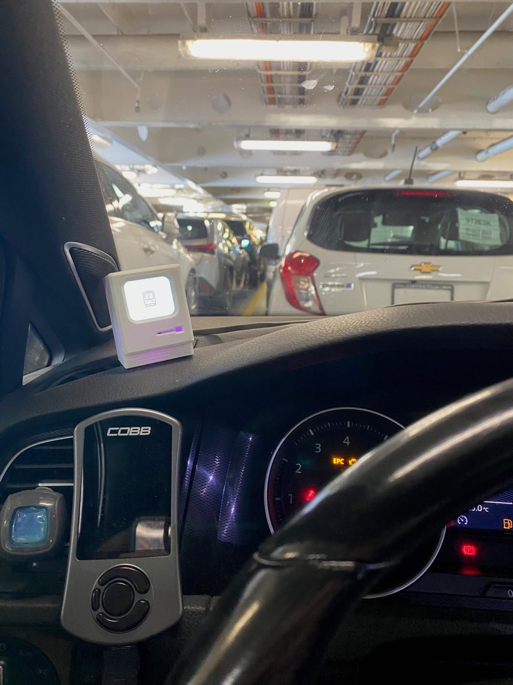 Miniature Macintosh-inspired Spotify album cover display in a car